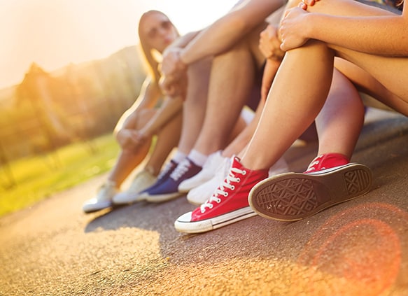 Legs-and-sneakers-of-teenage-boys-and-girls-sitting-on-the-sidewalk