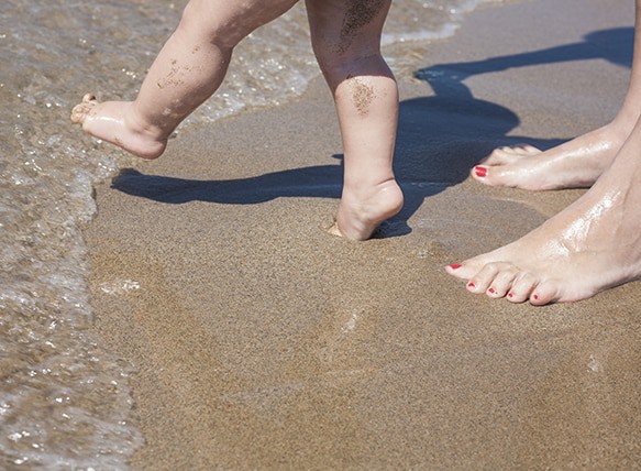Mother-and-baby-feet-walking-on-sand-beach