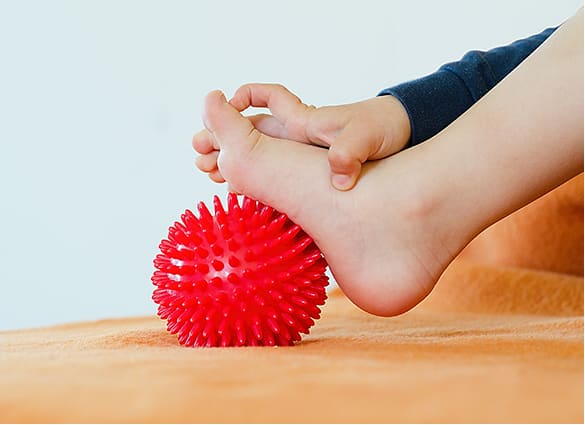 Toddler-massaging-with-ball-his-foot