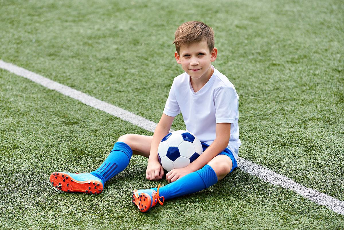 boy-soccer-pitch-sitting-boots-ball
