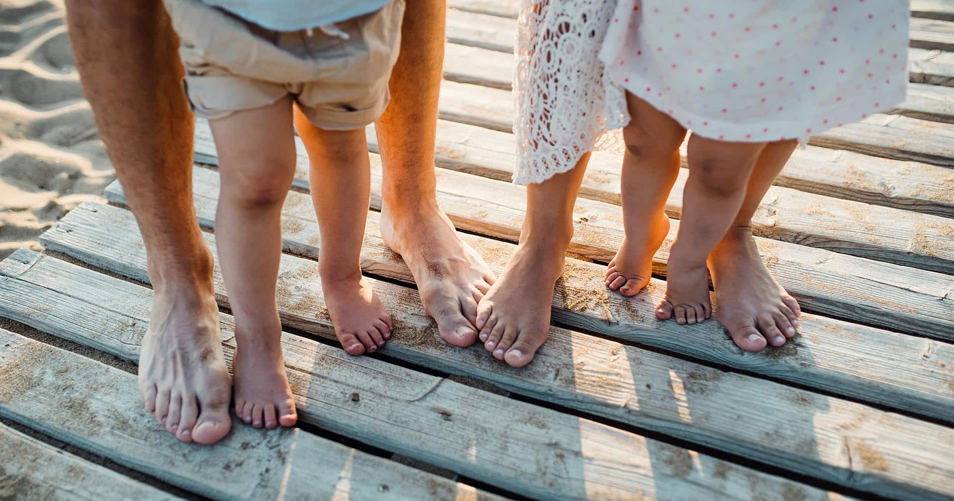legs-and-feet-of-family-standing-on-beach