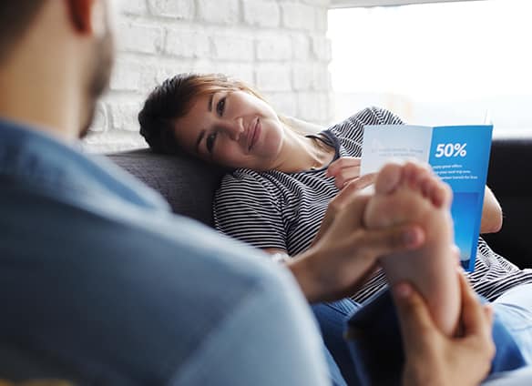 man-massaging-girlfriend-feet-on-sofa-at-home